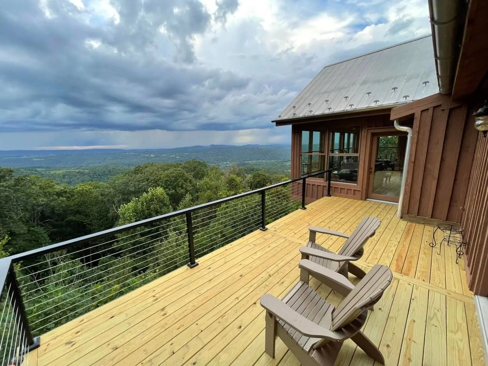 Wood deck with black cable railing overlooking a mountain valley